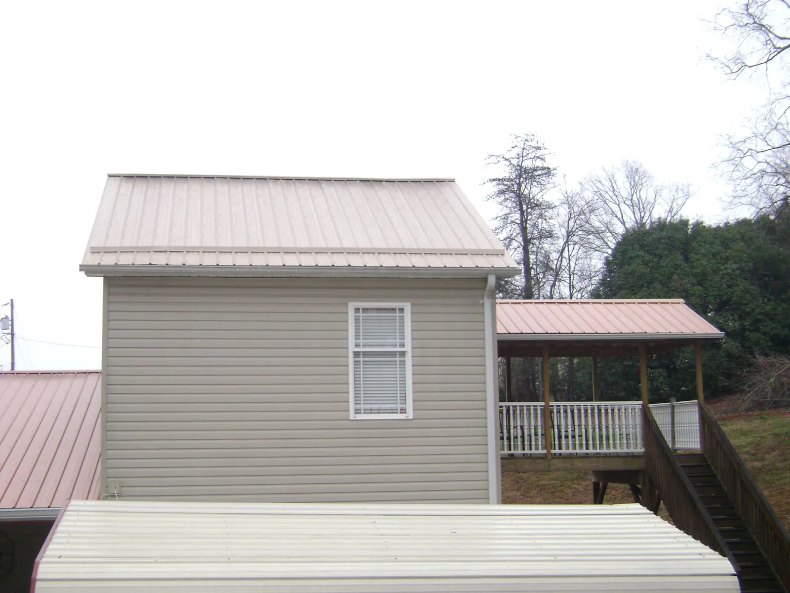 Tan metal roofs on a two story addition and attached porch, from a Roof Replacement job in Berwyn