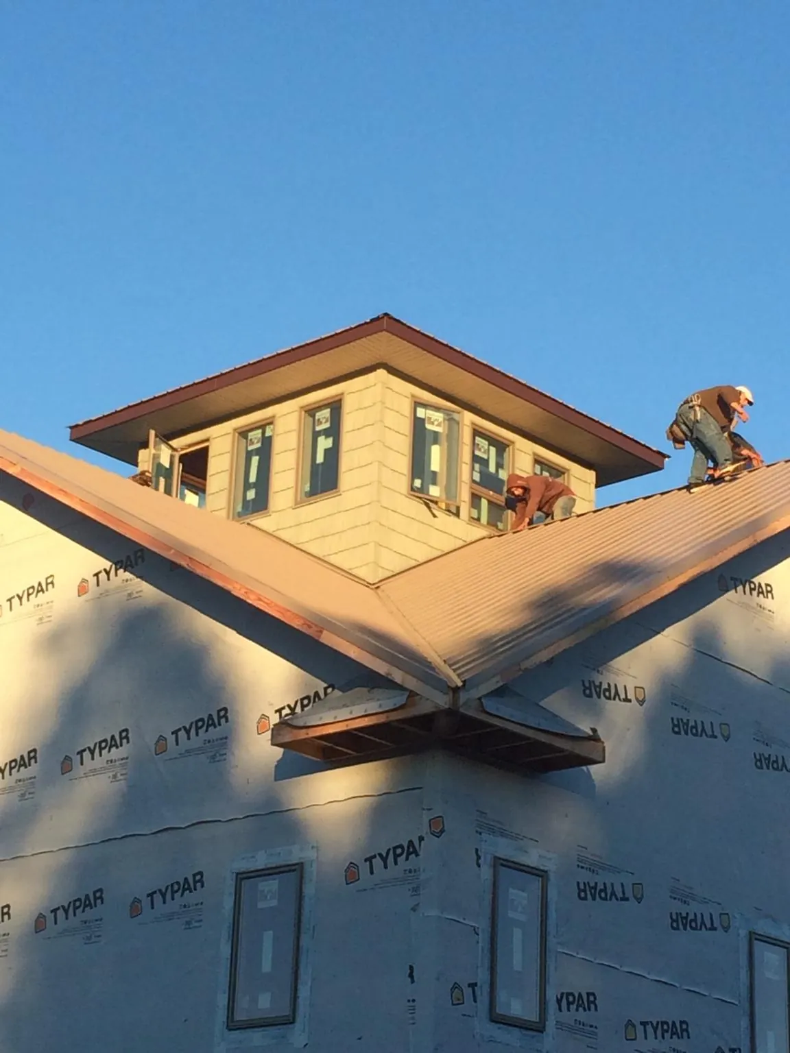 Roofers working around a rooftop cupola on a new metal roof at sunset — Roof Waterproofing in Berwyn by Roofing Brothers